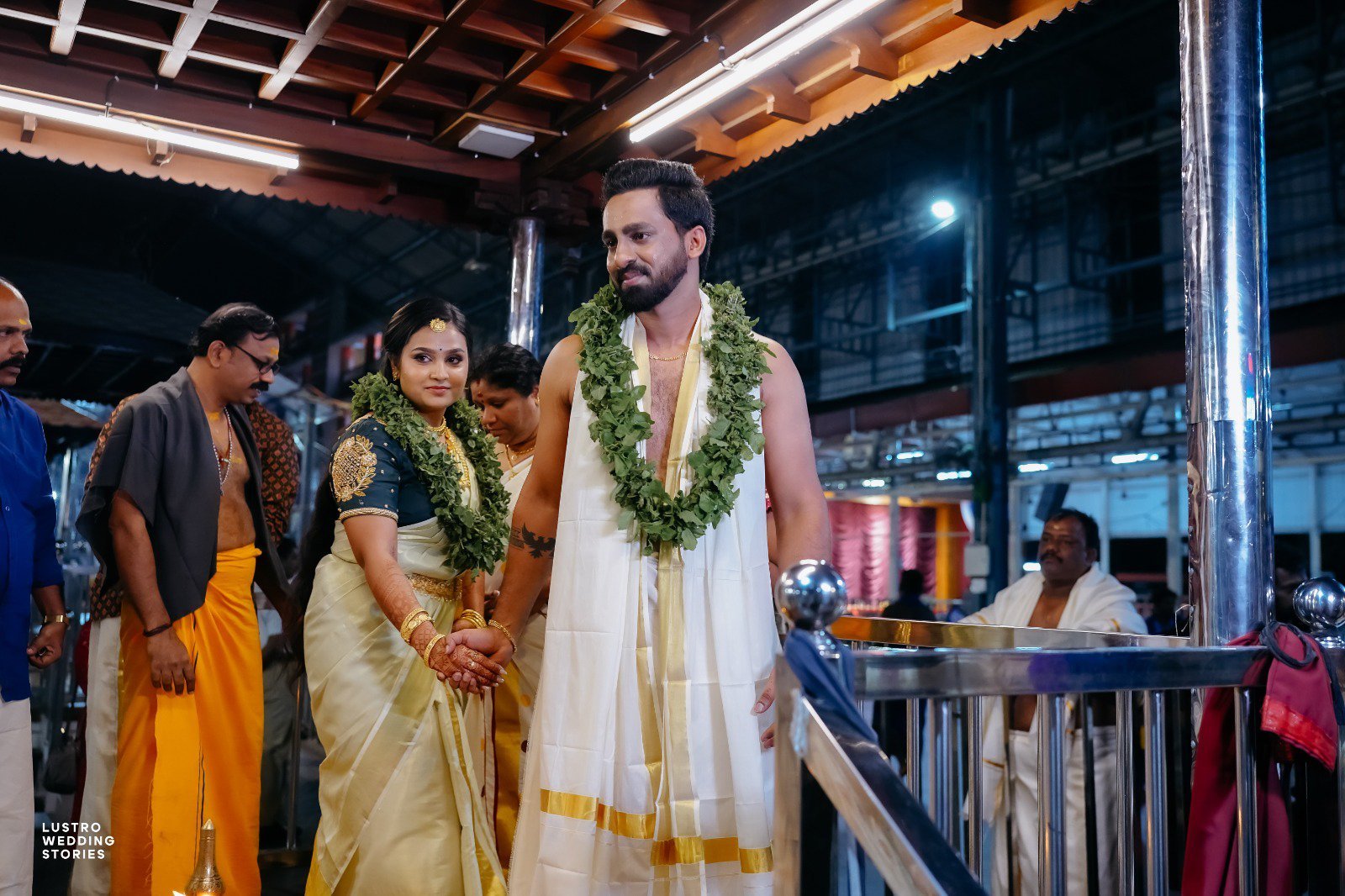 Guruvayur Temple Wedding Couple holding hands during sacred rituals at Guruvayur temple marriage ceremony with family members present